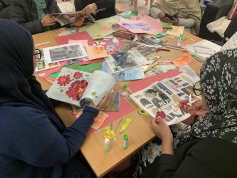 A group of young girls making a collage out of magazines and different paper