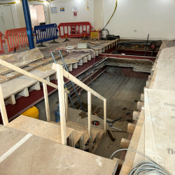 A photo showing a floor that has been cut through to make space for a new set of stairs.