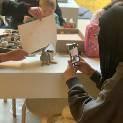 A photo of a young girl who has made an imaginary animal and has drawn a picture of it 