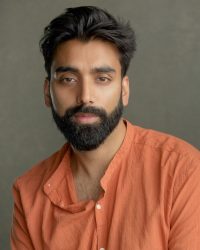 Headshot of a South Asian man wearing an orange shirt