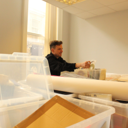 A man dressed in black looking through a box of CD's