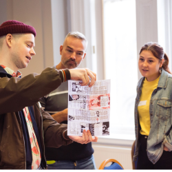 a photo of 3 people looking at a newspaper