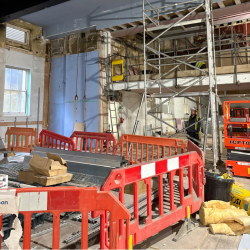 A photo of inside of a building site with scaffolding and barriers