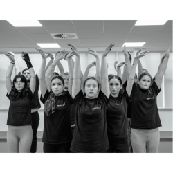 A photo of girls with their arms up dancing in a studio