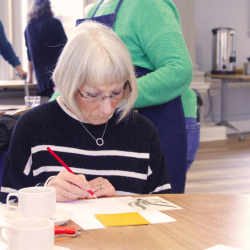 A photo of an elderly lady doing lino printing