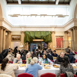 A group of people sharing a meal at an open Iftar inside of a museum